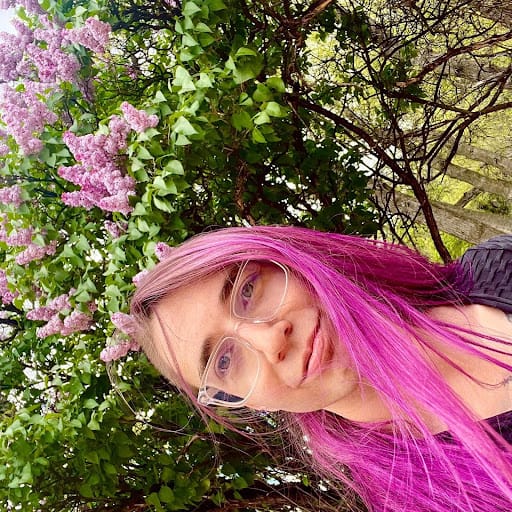 Blair, with long pink/purple hair and matching lilacs in bloom behind him; photo is posted sideways.