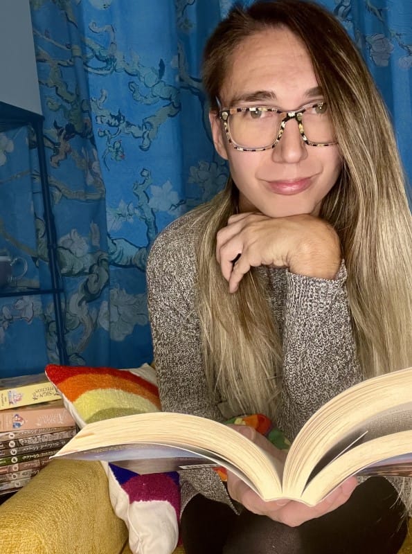 Blair looking at you while paused over an open book.