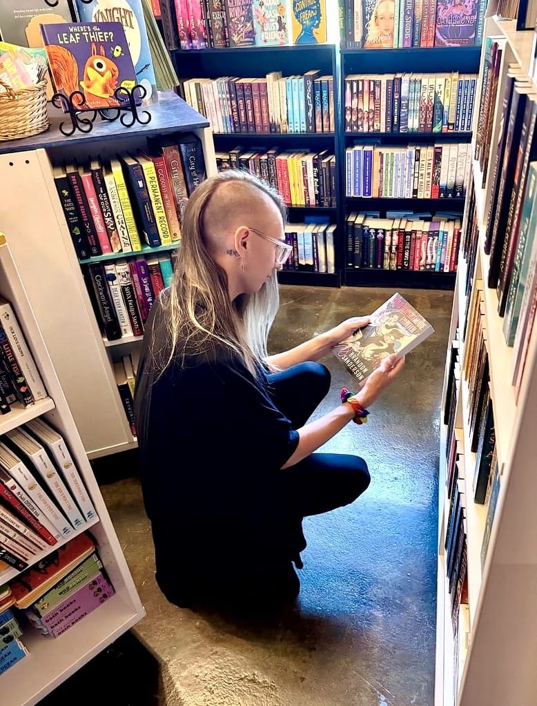 Blair kneeling in a book store to admire a book. (Yes, he bought it.)
